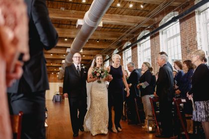 bride escorted by parents down the aisle